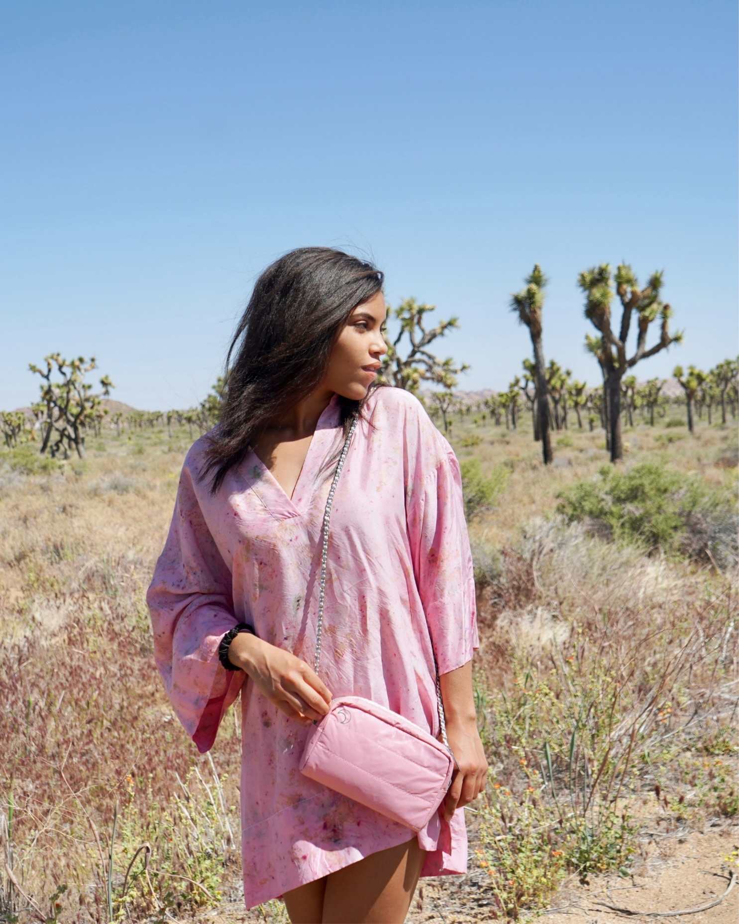Person holding a pink purse with moon shaped keychain and chain strap