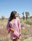 Person holding a pink purse with moon shaped keychain and chain strap in the desert.