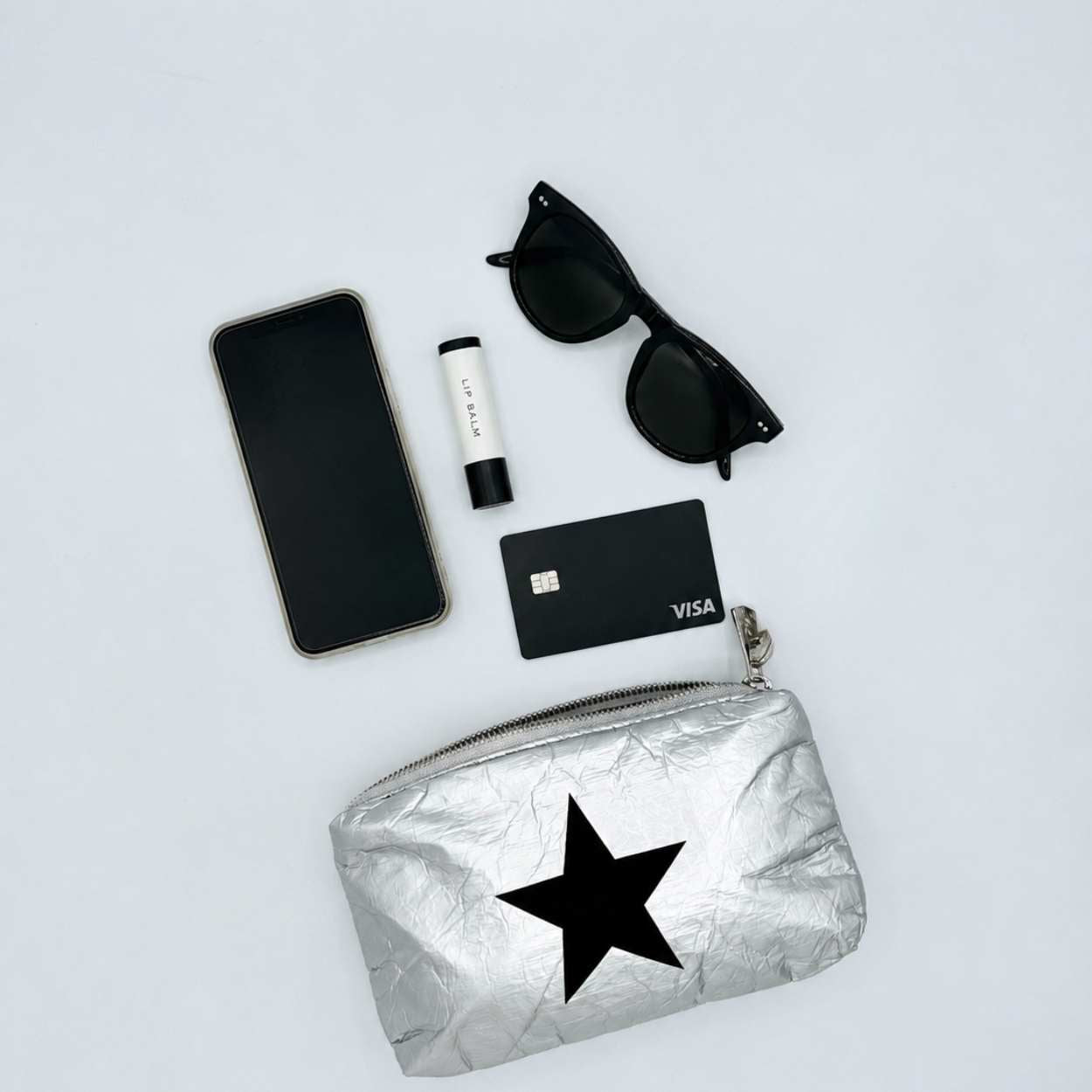 Mini Zipper Pouch Silver Black Star with cell phone, sunglasses, lip balm and credit card.