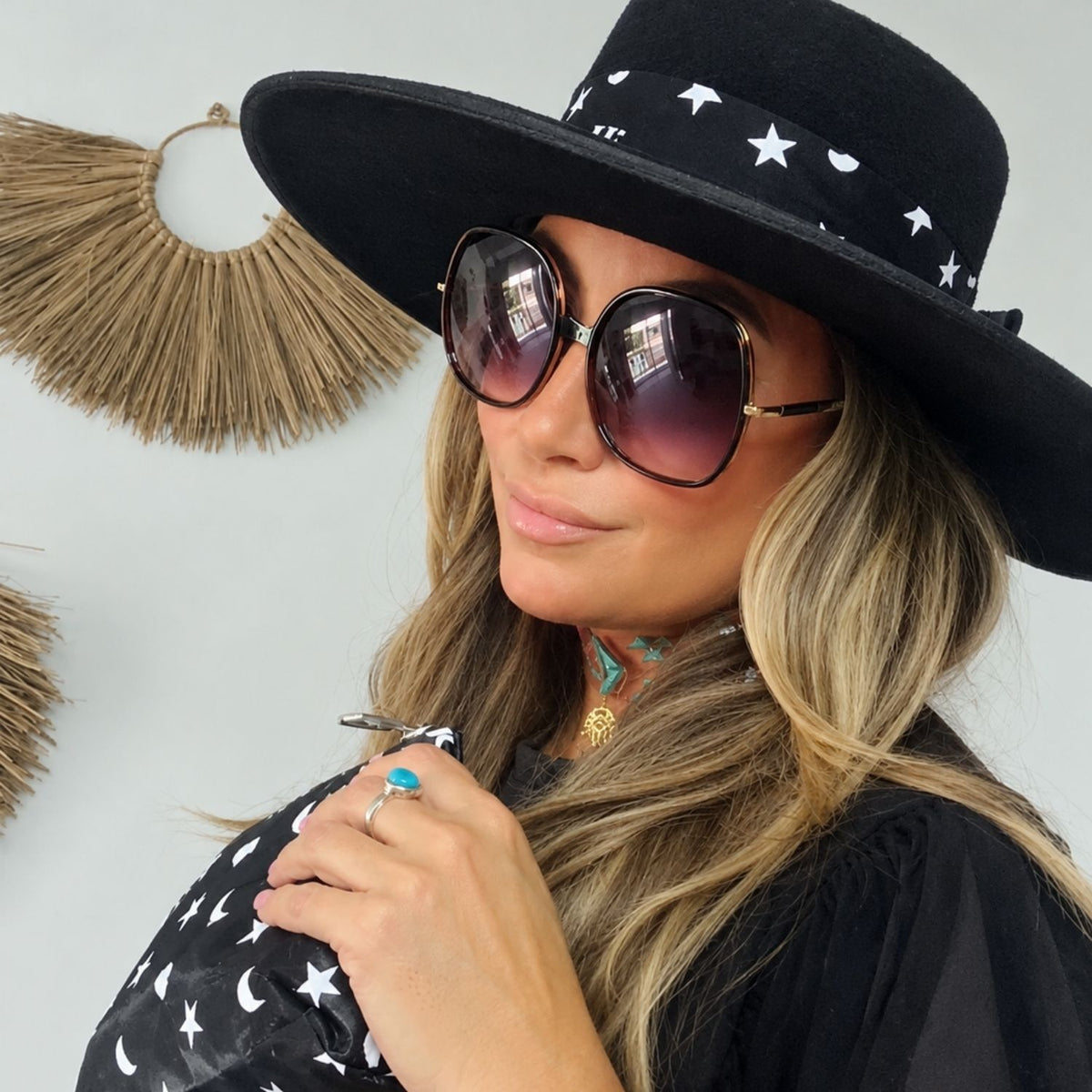 Woman in a western hat with matching silk hat band in black with heart moon star and zipper Pouch in the same pattern.