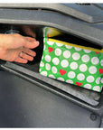 Hand placing a green pouch with white golf balls and red hearts into a golf cart.