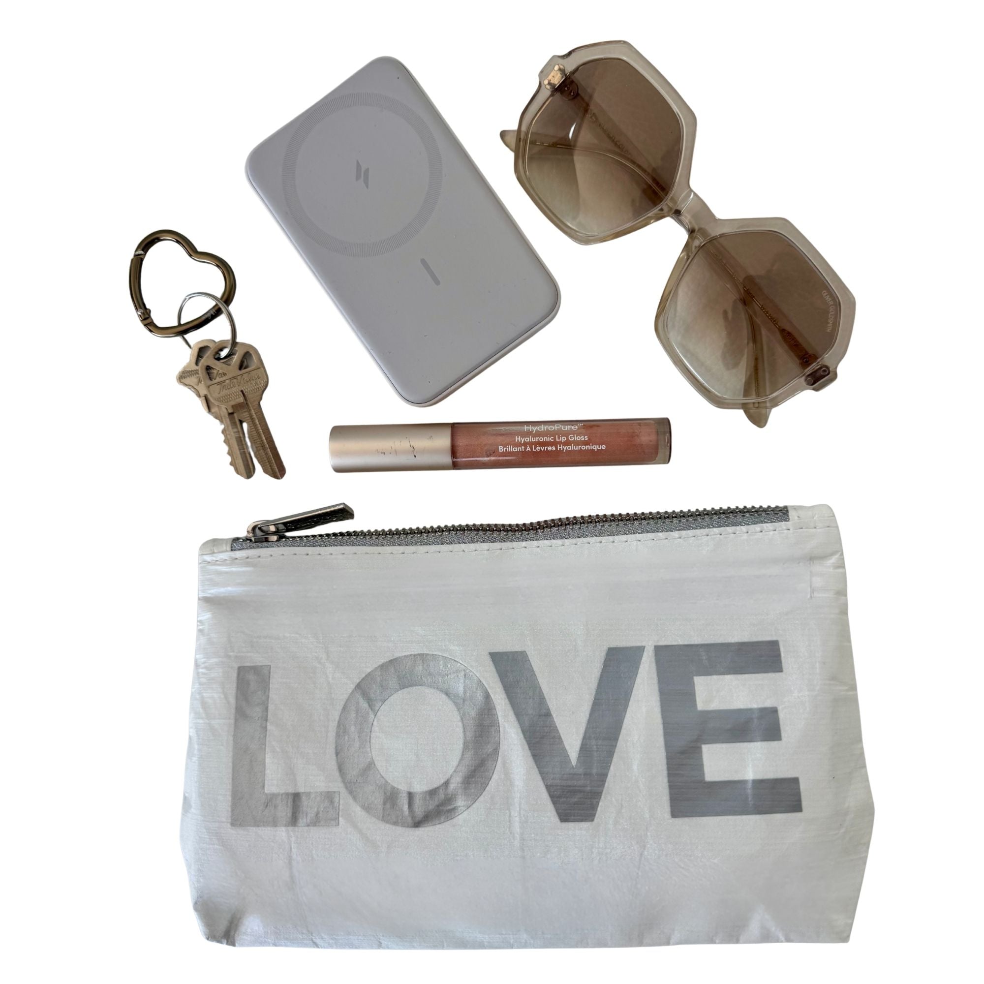Small White pouch with LOVE printed on it with sunglasses, lip balm, charger and keys on white background
