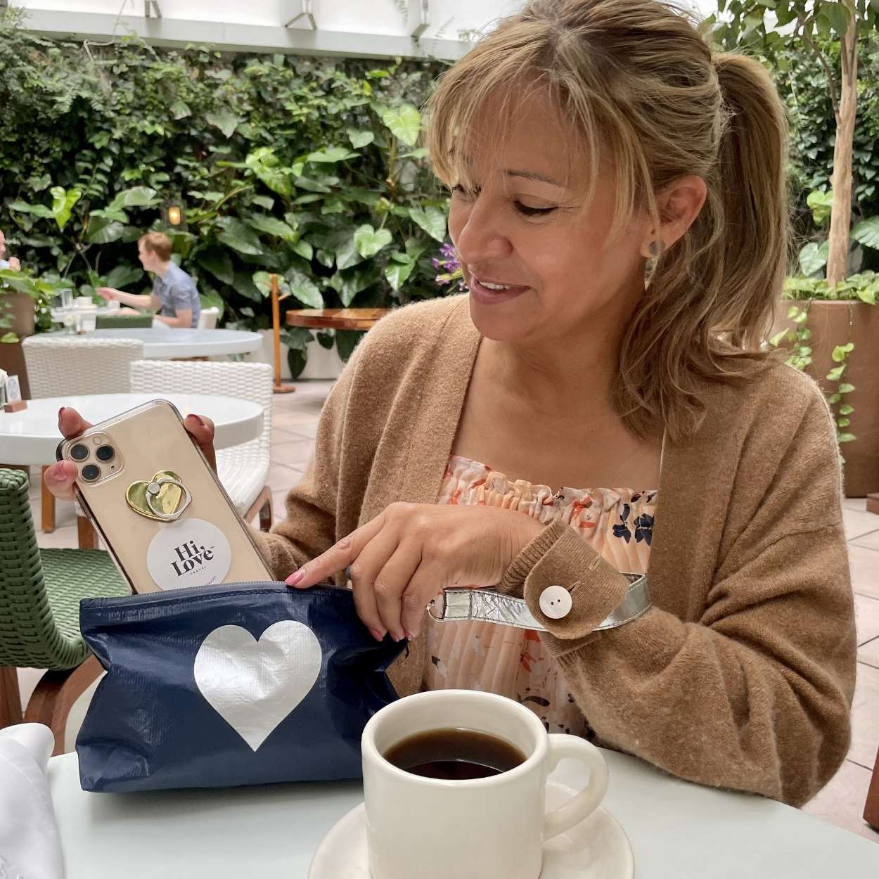 woman removing cell phone from her pouch in cafe