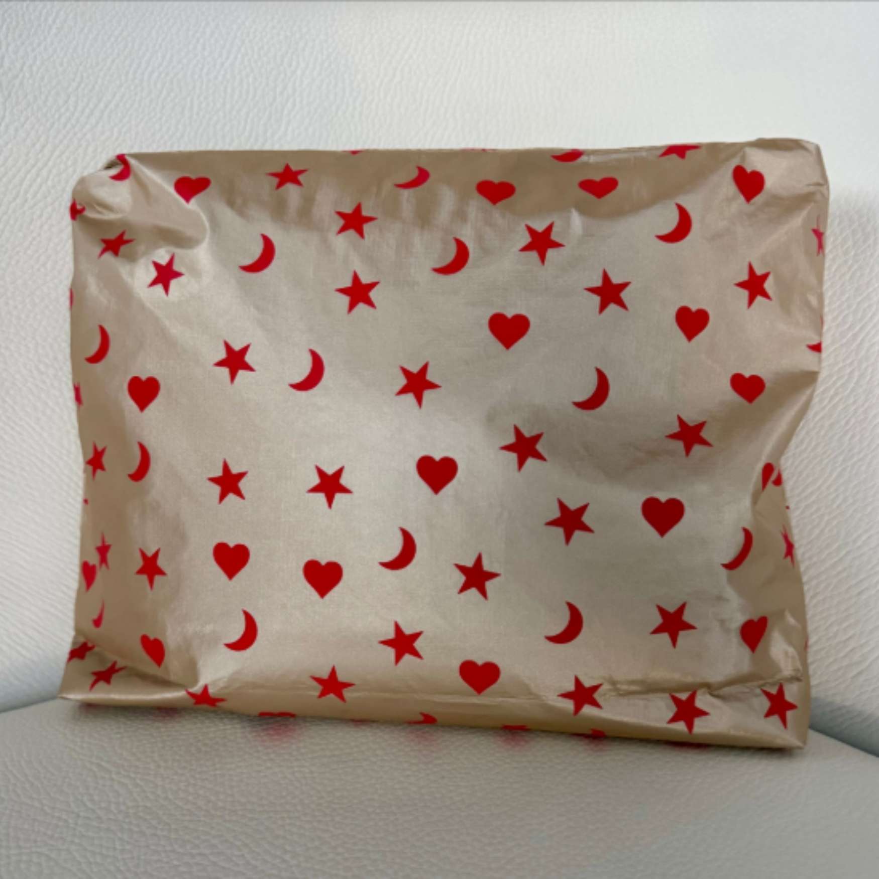 Beige shimmer medium pouch with red heart, moon, and star print.