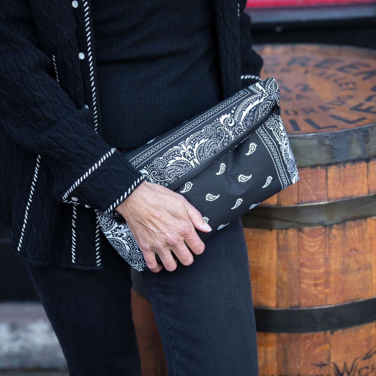 Person outdoors holding clutch purse in black bandana print