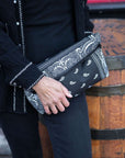 Person outdoors holding clutch purse in black bandana print