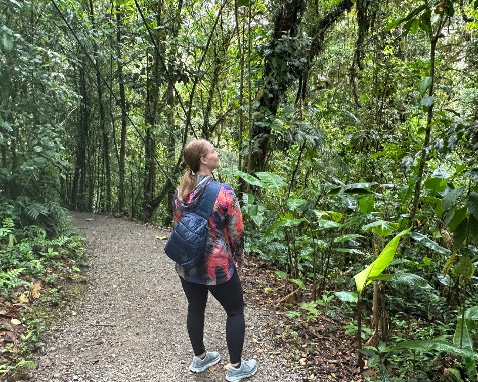 Woman in forest on hiking trail wearing leggings and crossbody backpack in shimmer navy blue with tonal star