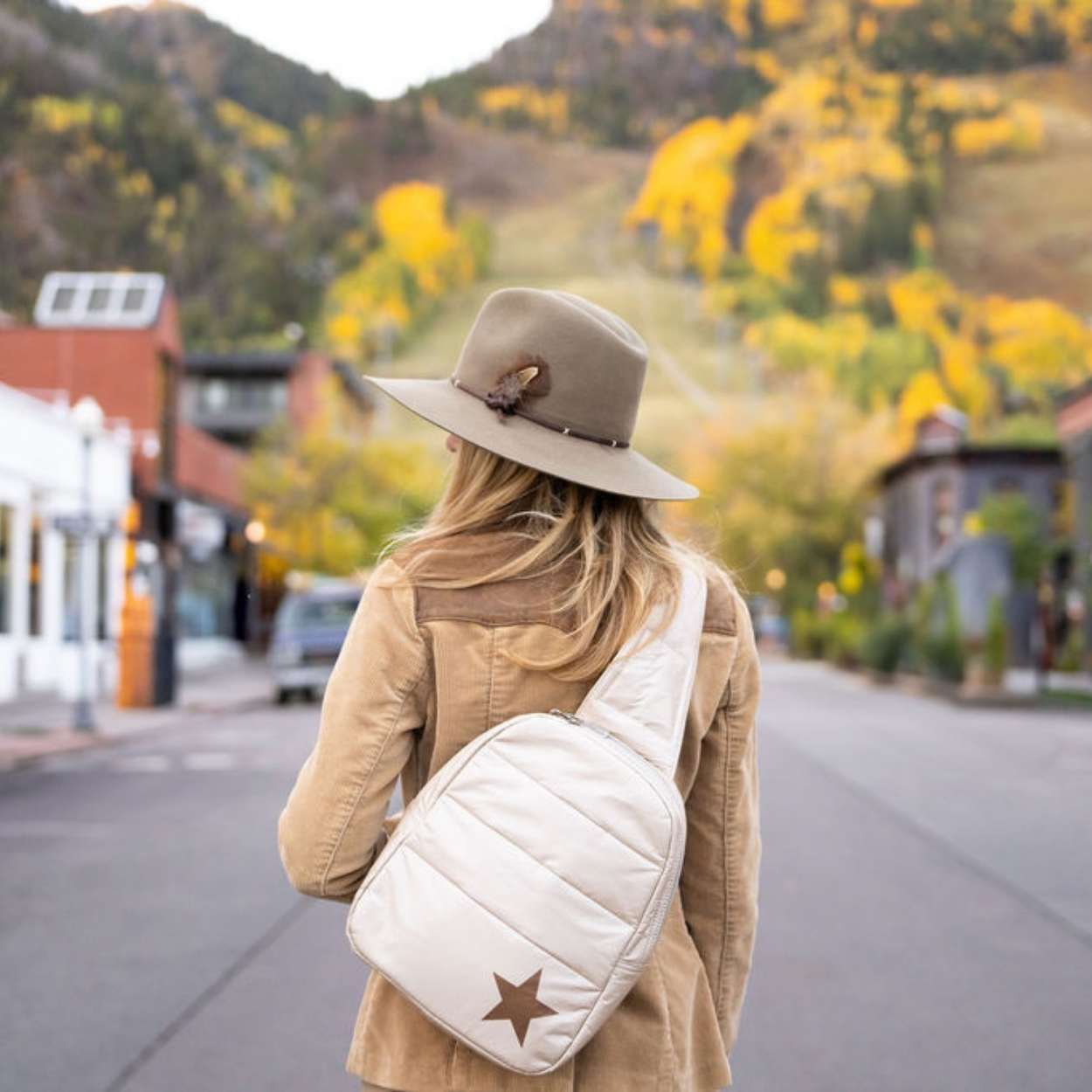 Woman outdoors wearing crossbody backpack in shimmer beige with star
