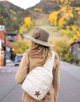 Woman outdoors wearing crossbody backpack in shimmer beige with star