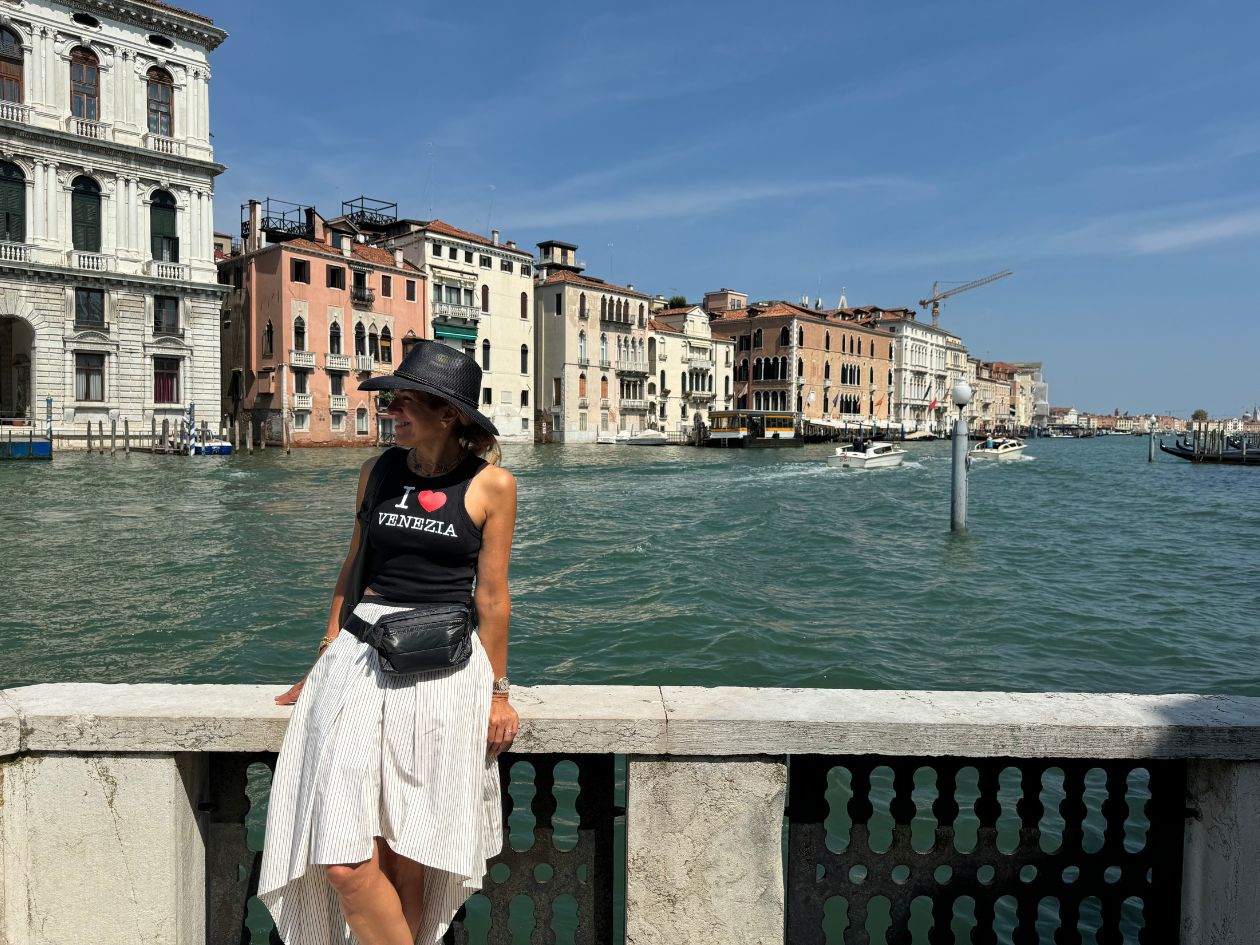 Woman standing with water background wearing Puffer Crossbody Fanny Pack Belt Bag in Shimmer Black