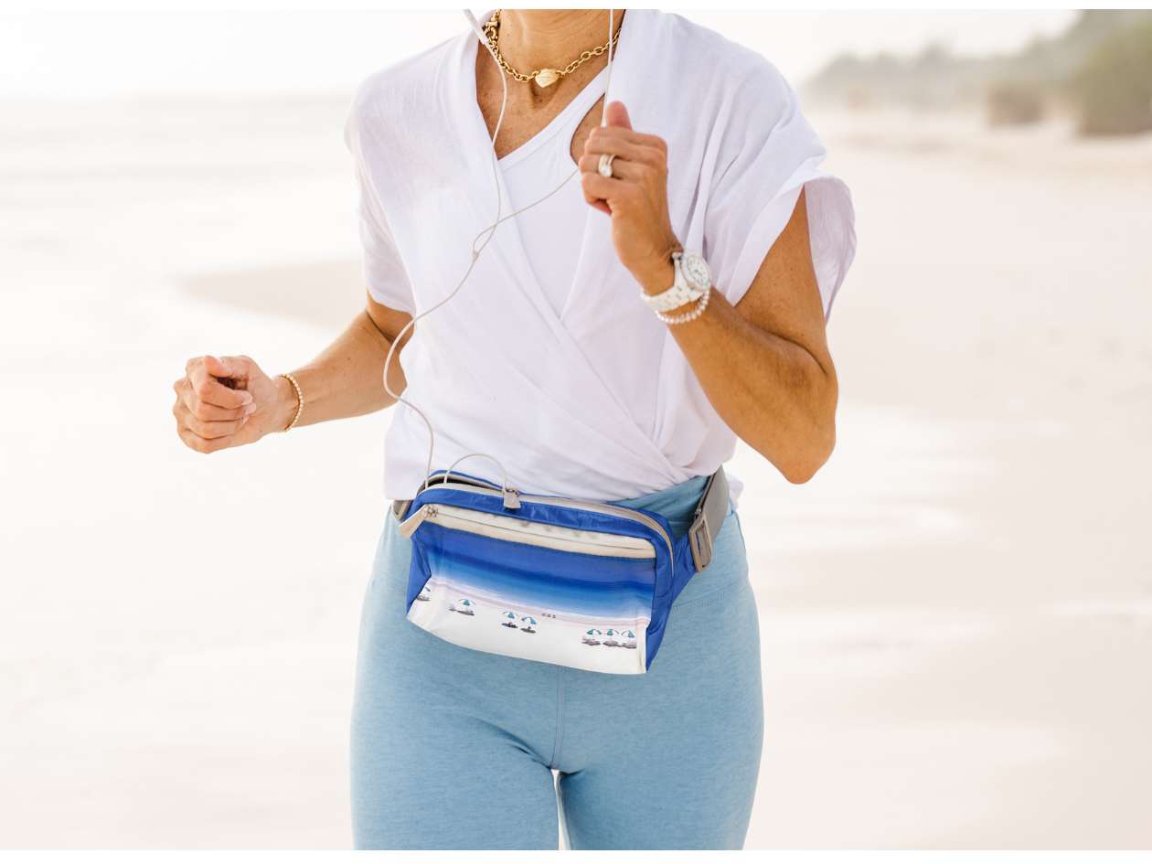 Woman running on beach wearing puffer fanny pack belt bag in harbor island beach scene print