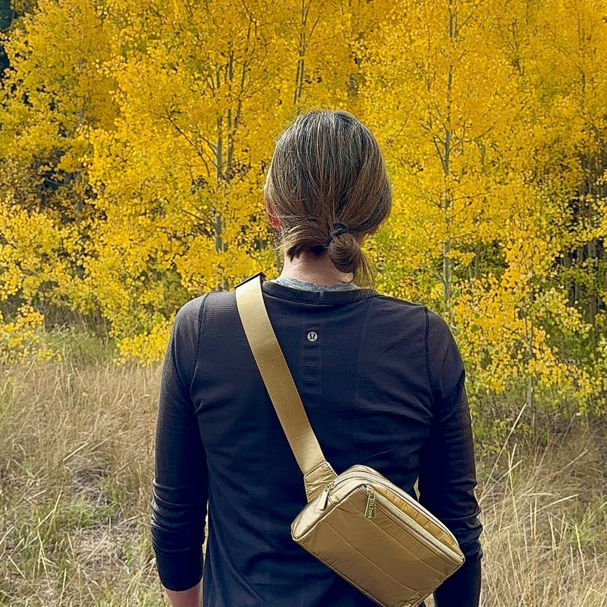 Woman in nature carrying crossbody fanny pack belt bag in gold