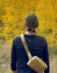 Woman in nature carrying crossbody fanny pack belt bag in gold