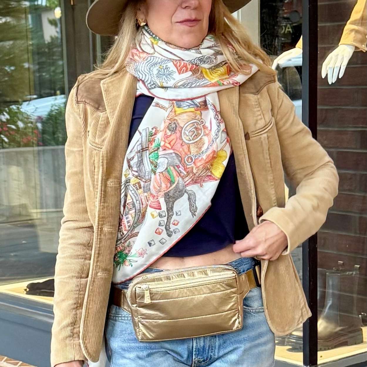 Woman wearing brown coat and printed scarf with puffer fanny pack belt bag around waist 