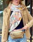 Woman wearing brown coat and printed scarf with puffer fanny pack belt bag around waist 