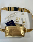 Puffer fanny pack belt bag in gold with travel accessories on white