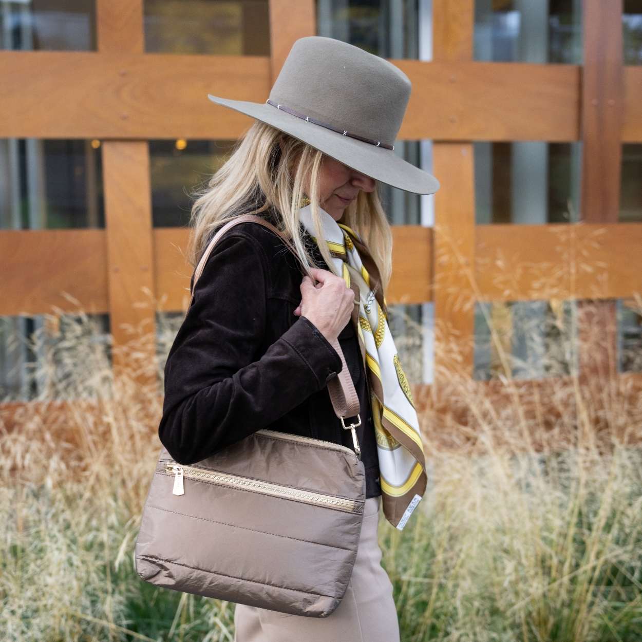 Woman outdoors wearing bronze puffer purse and western hat