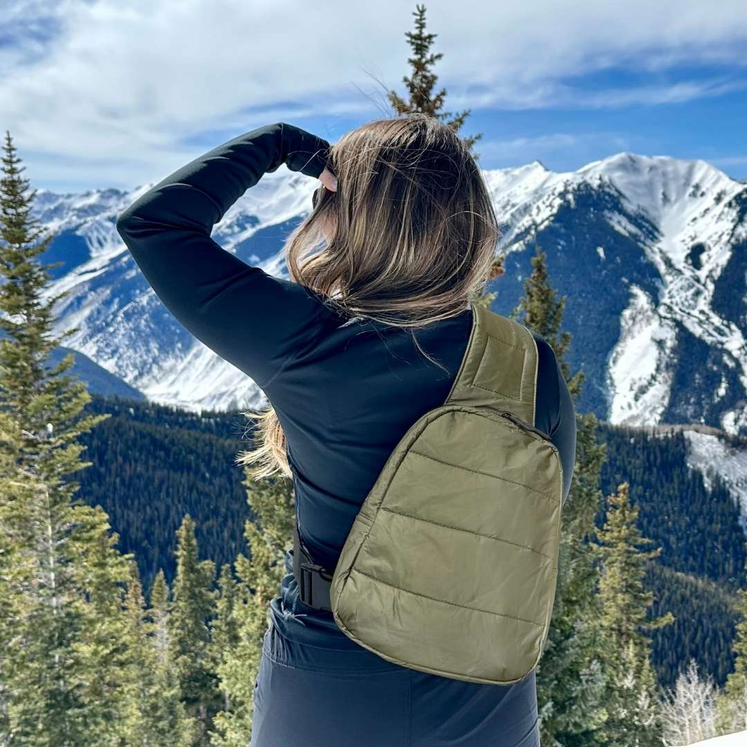 Person with a green backpack looking at snow-capped mountains