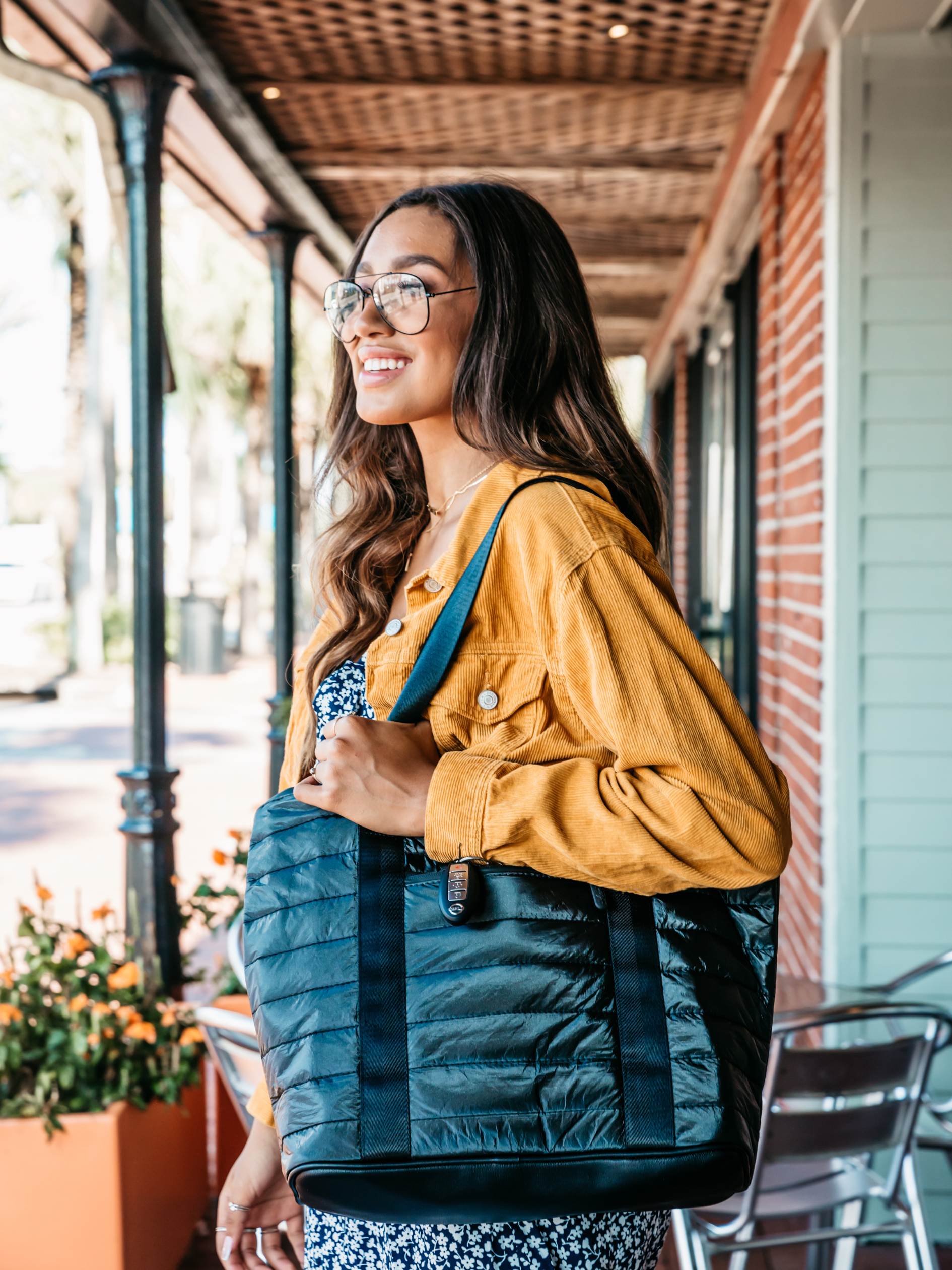 Woman holding a shimmer black tote bag on a city street