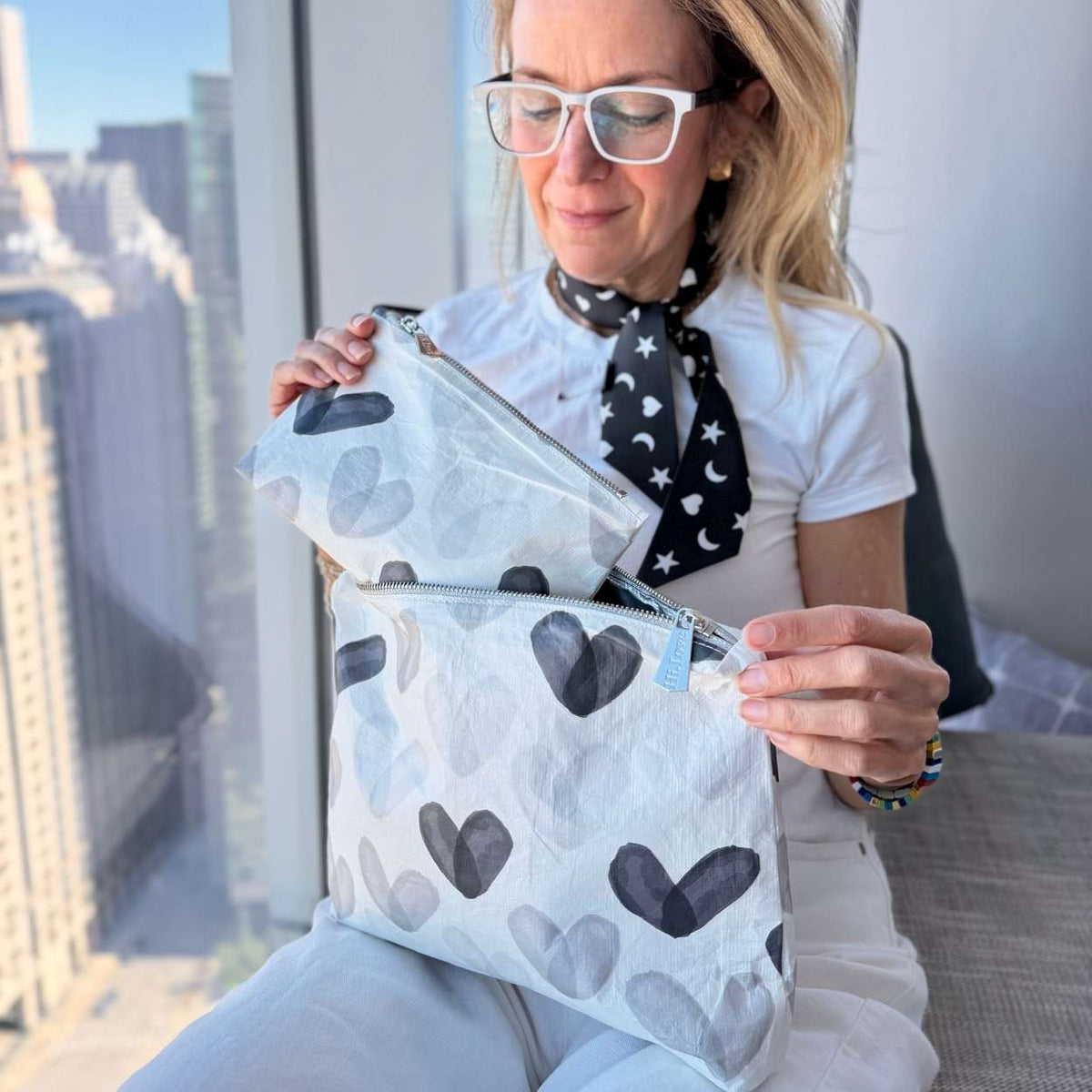 Woman in all white outfit holding Set of Two Zip Pouches Language of Love Black and White Heart Print with city background