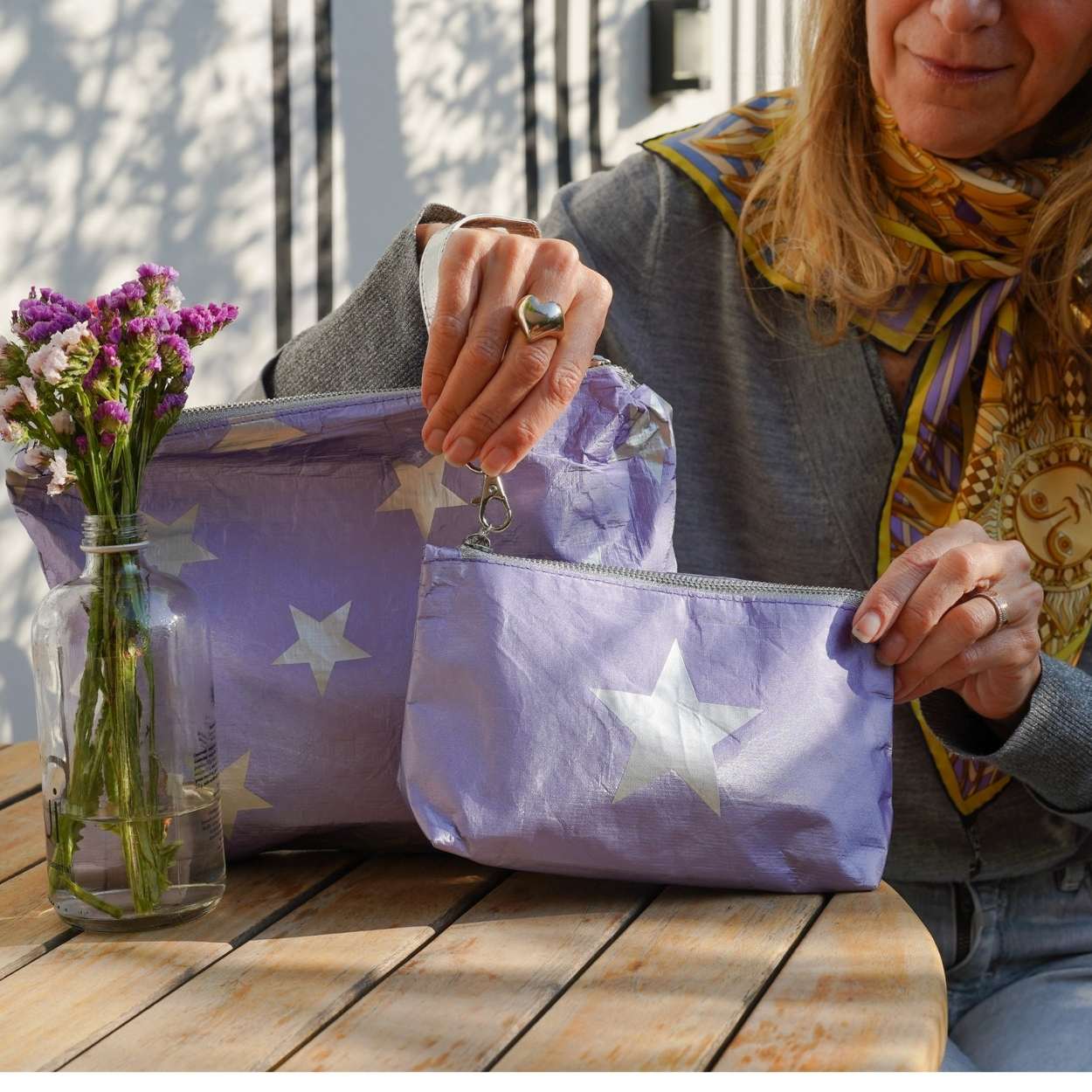 Person opening a set of two purple pouches with star patterns on a wooden table