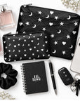Set of Two Zipper Pouches in Black with Heart Moon Star Print with phone, keys, lip balm, notepad, scrunchie and perfume on white background