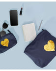 Two navy pouches with heart of Gold emblem, passport, phone, lipstick, notebook, pen on a light blue background