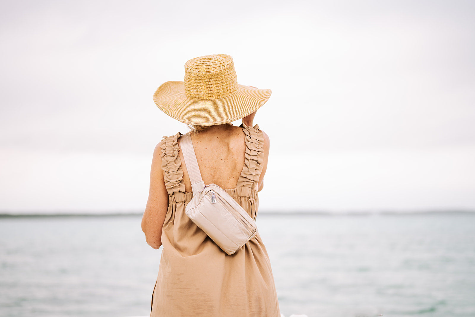 Woman by water wearing Shimmer Beige Puffer Crossbody Fanny Pack Belt Bag