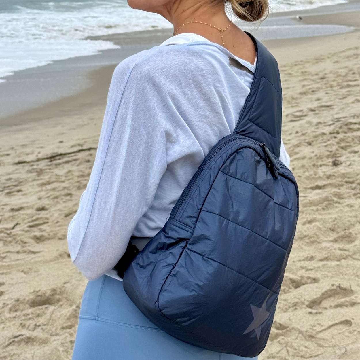 Person on beach with crossbody backpack in shimmer navy with tonal star