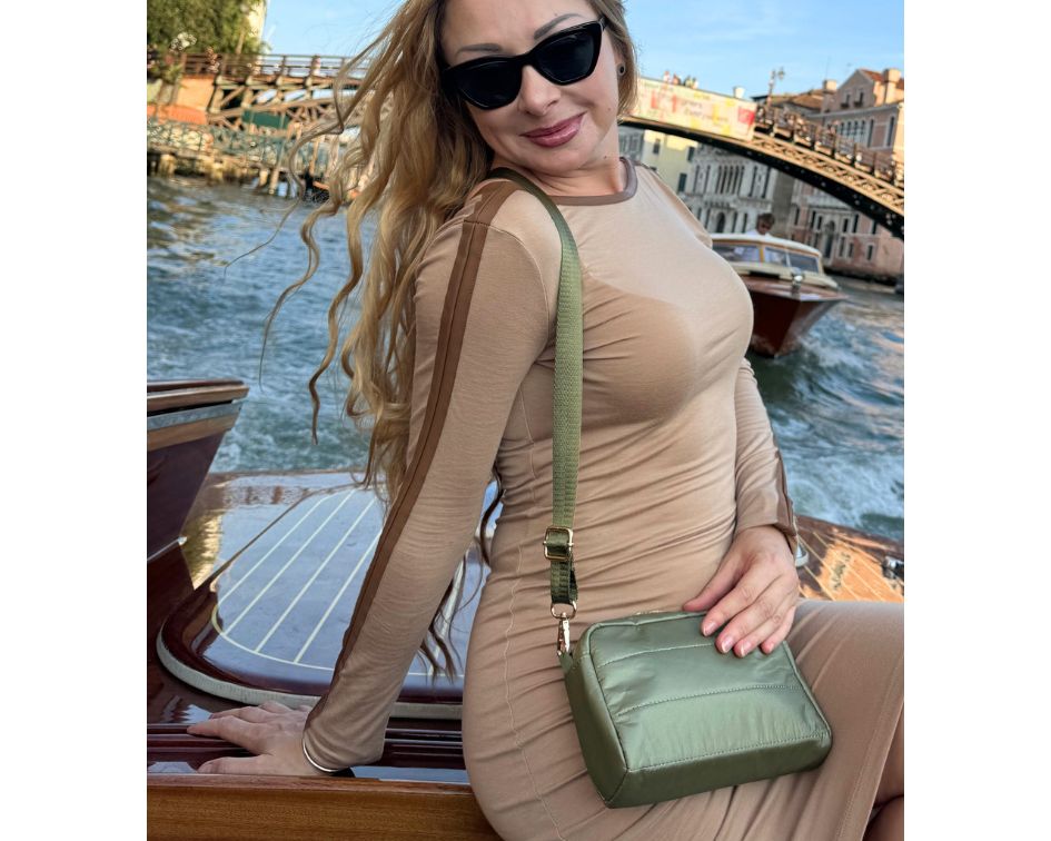 Woman sitting on boat in Italy wearing brown dress and shimmer army green crossbody purse