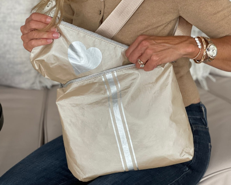 Person holding crossbody shimmer beige pouch to purse with silver stripes and mini pouch in shimmer beige with silver heart
