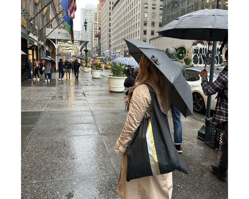 Woman with umbrella and Black Stripe tote bag standing in city