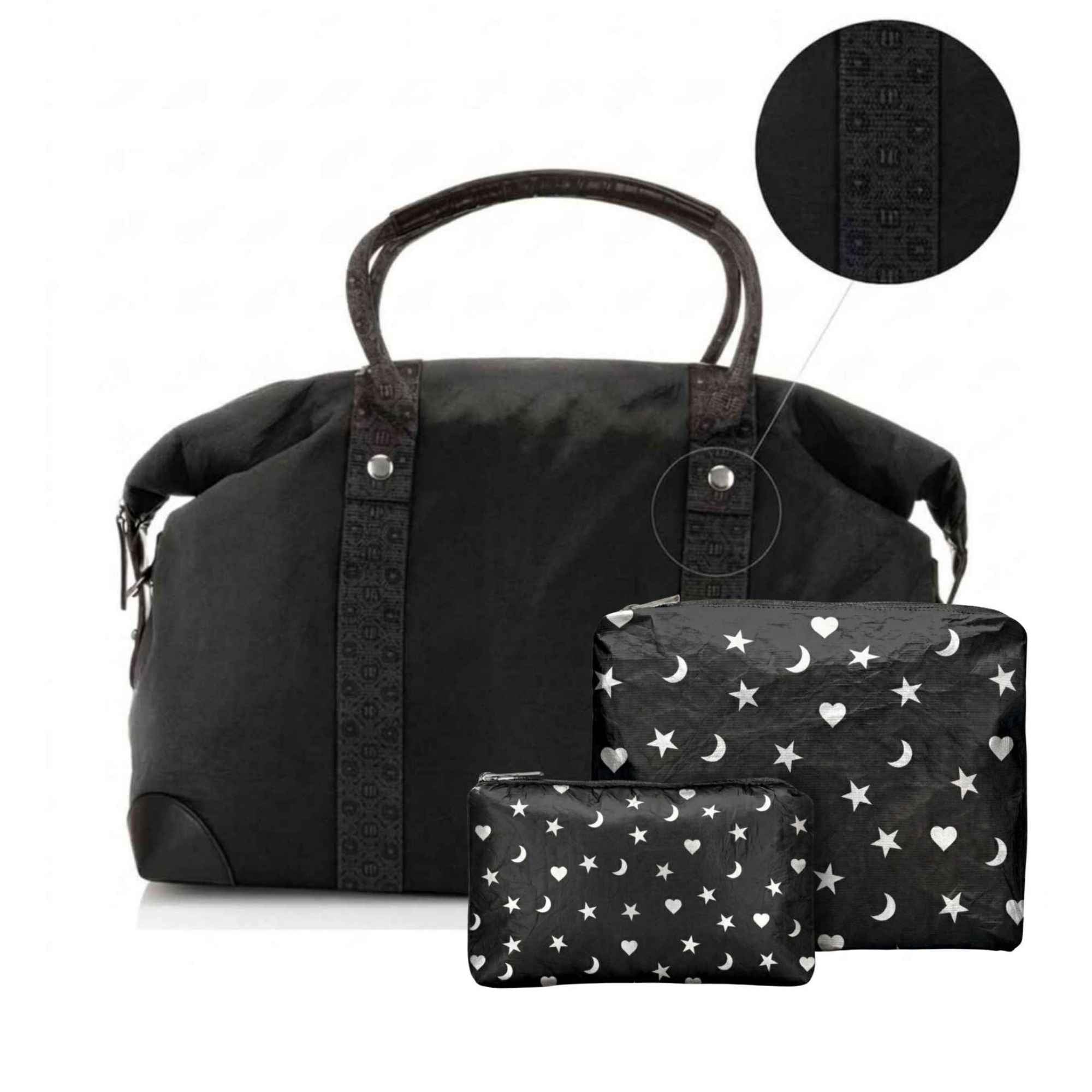 A black duffel bag with signature print handles and side trim, shown with two matching zip pouches in front. The pouches have a white star and moon pattern, and a circular inset at the top shows a close-up of the black patterned strap detail.