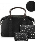 A black duffel bag with signature print handles and side trim, shown with two matching zip pouches in front. The pouches have a white star and moon pattern, and a circular inset at the top shows a close-up of the black patterned strap detail.