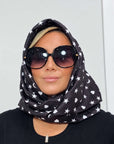 Model wearing the black Signature scarf with white hearts, moons and stars wrapped around her head like a hood.