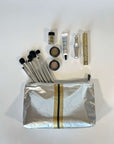 Makeup set with a gold and silver stripe zipper pouch on a white background