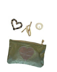 Green pouch with heart design and hair accessories on a white background