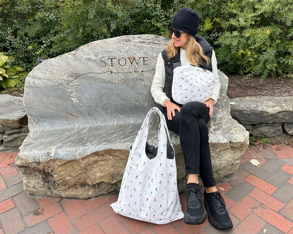 Woman sitting on 'Stowe' bench holding skier patterned bags