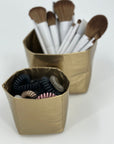 Travel cups set in gold with makeup brushes and hair ties inside