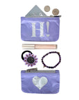 Purple pouch with 'H!' and heart design, containing coins, a lip balm, hair tie, and bracelet on a white background.