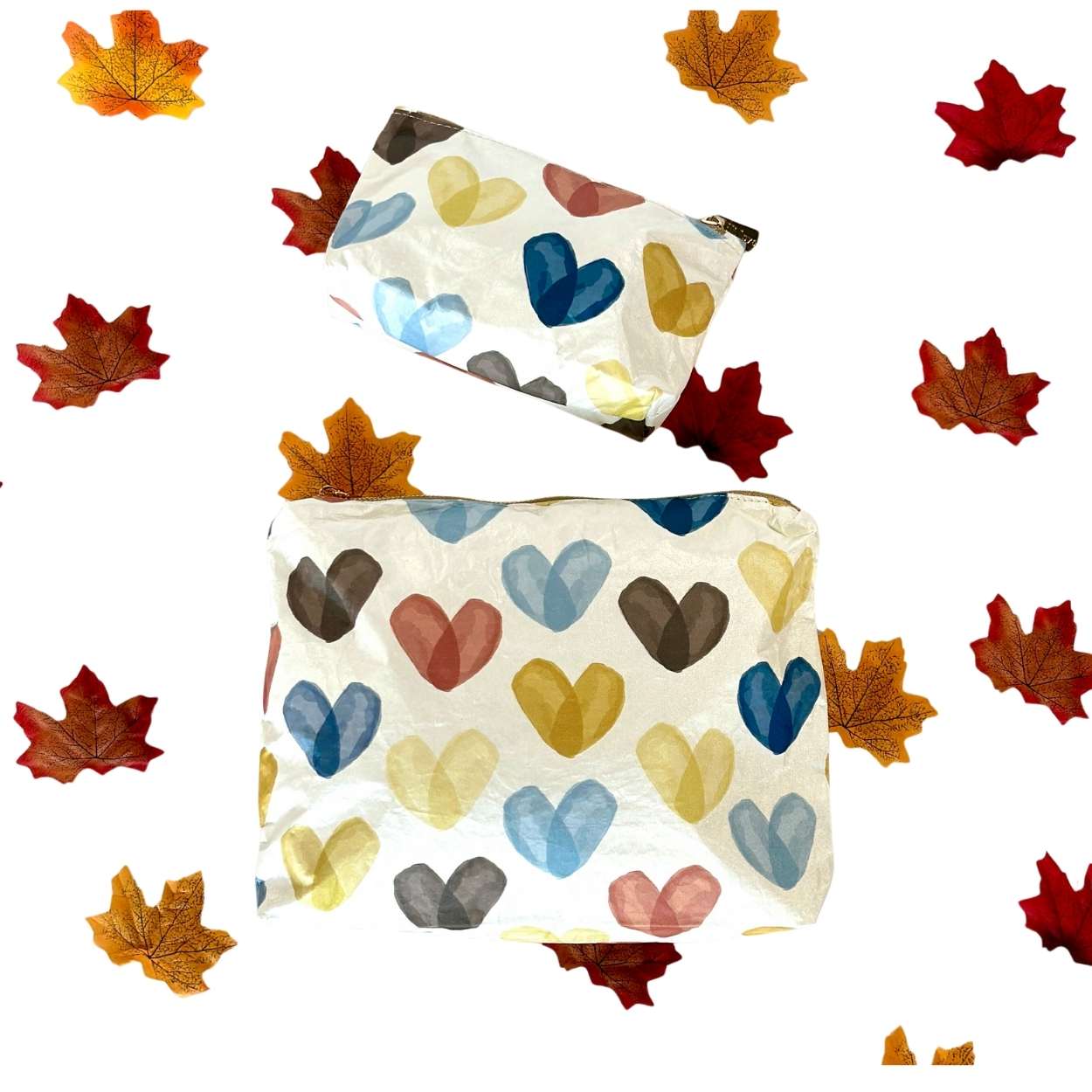 Two Pouches with colorful heart patterns on a white background with autumn leaves.