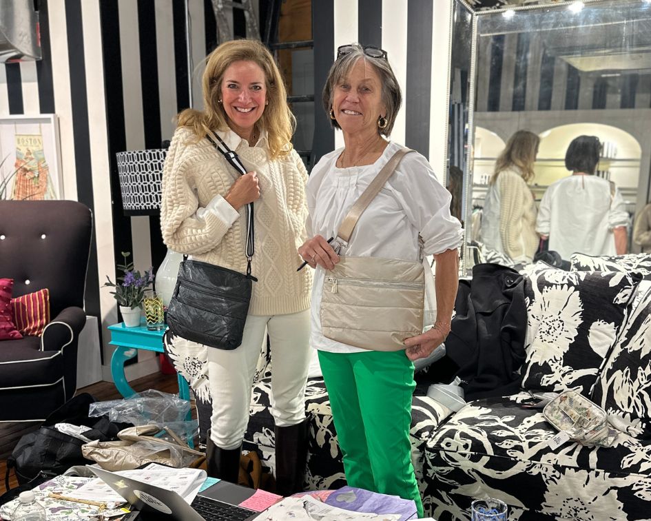 Two women in black and white room holding crossbody purses