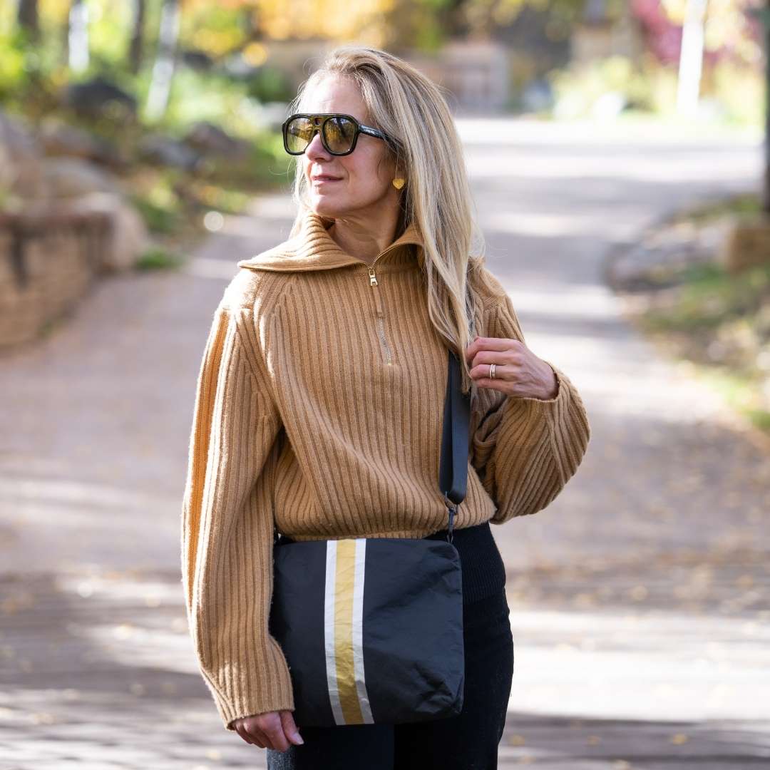 Woman wearing a tan sweater and sunglasses outdoors