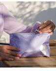Person holding a purple pouch with a heart design outdoors