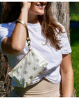 Woman holding a patterned pouch with bees outdoors
