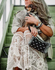 Woman carrying black bandana print wristlet with dog on green stairs