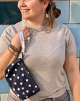 Person holding a navy blue bag with white star patterns against a blue tiled wall.