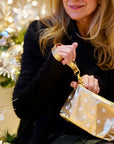 Woman in black sweater holding zip wristlet in gold with myriad of white stars