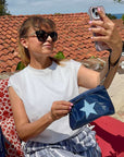 Woman taking selfie outdoors hold zip wristlet in shimmer navy blue with light blue star