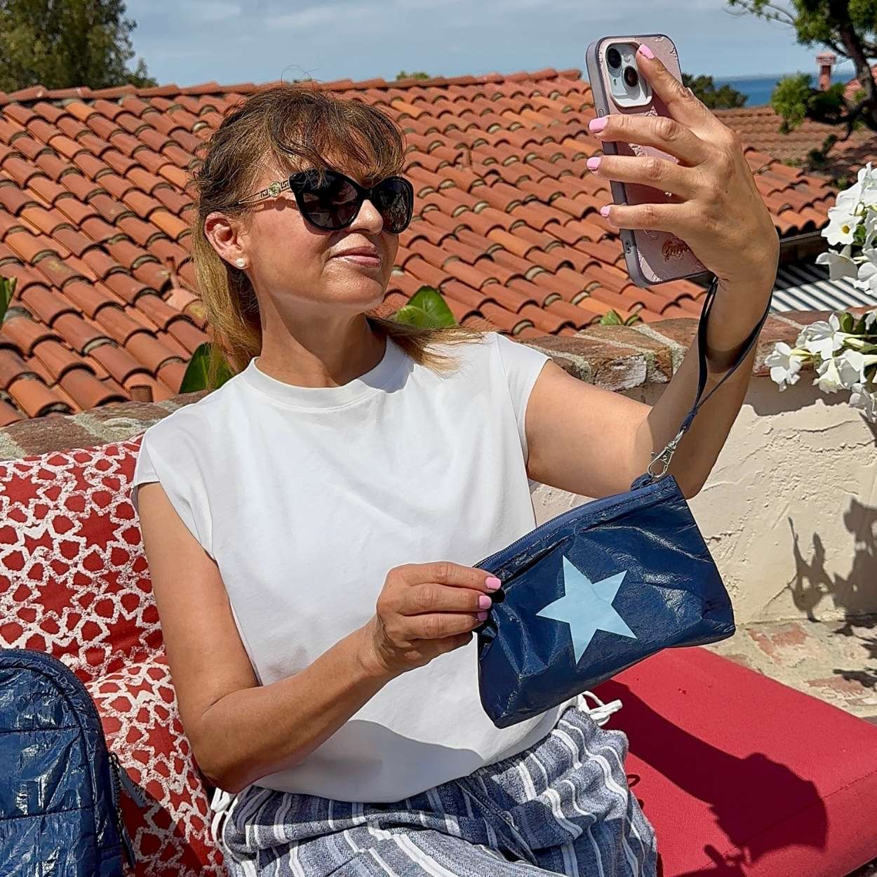 Woman taking selfie outdoors hold zip wristlet in shimmer navy blue with light blue star